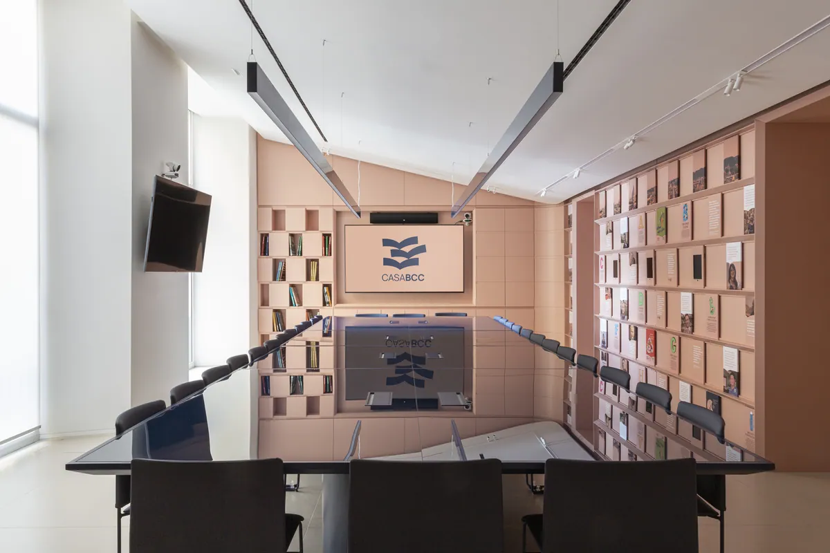 Sala conferenze con tavolo scuro, parete espositiva modulare e schermo BCC Roma