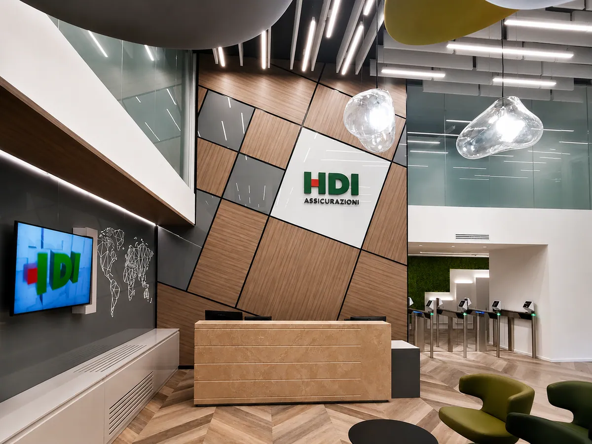 Reception HDI Assicurazioni con parete rivestita a moduli in legno e schermo informativo