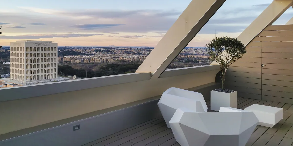 Terrazza panoramica con decking in legno, sedute bianche e vista sulla città