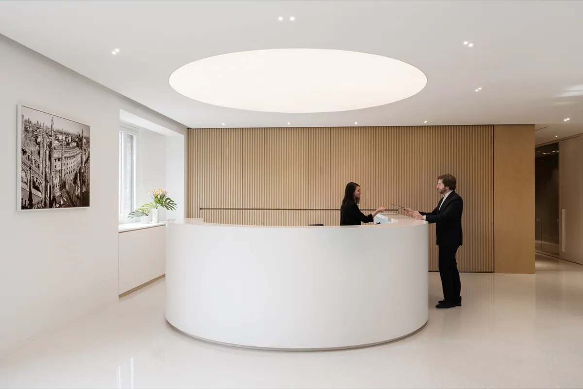 Bancone reception bianco curvo con parete a doghe in legno